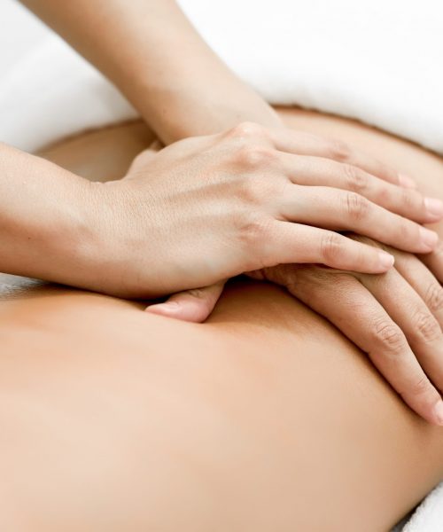 Young woman receiving a back massage in a spa center. Female patient is receiving treatment by professional therapist.